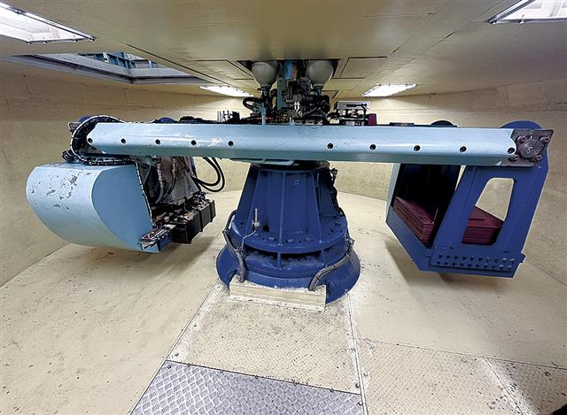 両端の装置に模型を載せる。回転中の模型に地震動を入力する振動台など補助装置も備える