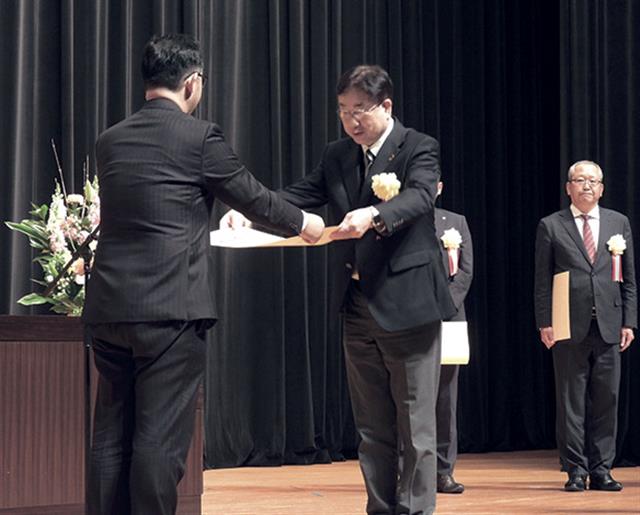 佐竹局長（左）から表彰状を受け取る尾形氏