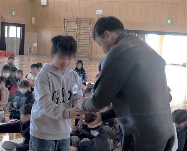 育てたアマモポットをダイバーに受け渡す小学生