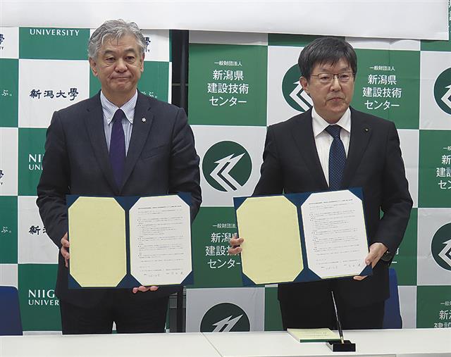 協定書を手にする深田理事長（右）と川端機構長