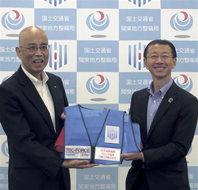 皆川会長（左）にＴＥＣ－ＦＯＲＣＥ（緊急災害対策派遣隊）のビブスを手渡す橋本局長