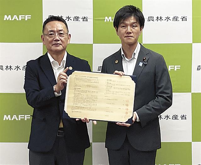 齊藤社長（左）と鈴木農水相が協定書を交わした