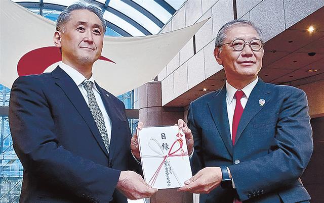 目録を手渡す功刀日建連常務執行役（右）